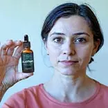 Audifort customer review — Sarah M. age 52, verified customer holding Audifort bottle, tinnitus relief testimonial